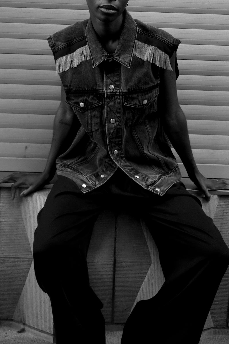 Our DALIA CHAINS off-black cotton denim jacket is the perfect blend of timeless design and modern style. Its raw-cut sleeves and signature hand-embroidered chains at the shoulders with dark green gros-grain tape and silver press buttons add a luxurious touch, giving it a boyish yet pure look. This jacket is sure to be your go-to for a timeless rock'n roll look. Boyfriend fit. Laetitia wears a size S 100% cotton, Made in Portugal