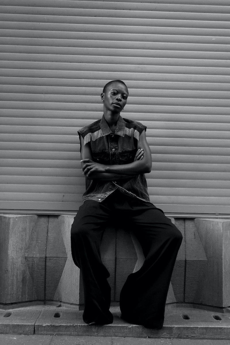 Our DALIA CHAINS off-black cotton denim jacket is the perfect blend of timeless design and modern style. Its raw-cut sleeves and signature hand-embroidered chains at the shoulders with dark green gros-grain tape and silver press buttons add a luxurious touch, giving it a boyish yet pure look. This jacket is sure to be your go-to for a timeless rock'n roll look. Boyfriend fit. Laetitia wears a size S 100% cotton, Made in Portugal