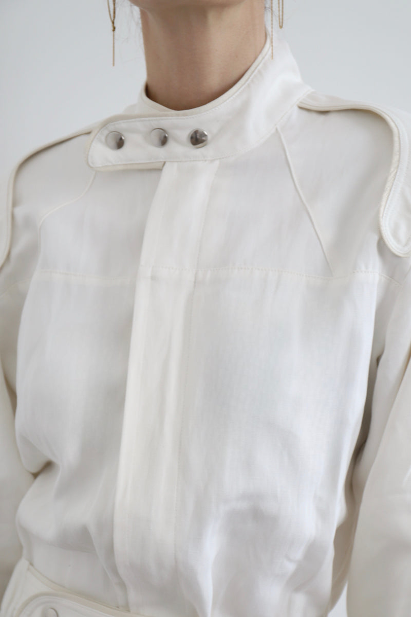 SARAH DE SAINT HUBERT Heritage racing jumpsuit with SDSH signature details. Beautiful silk-hemp fabric sourced from a Luxury House deadstock. Beige gros-grain finishings. Iconic rows of metal snaps at the collar and waist. Boyish and feminine look. Straight and relaxed fit. Made in Portugal