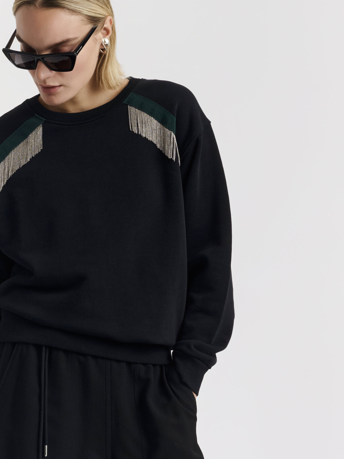 Black MARTY CHAINS sweatshirt with hand-embroidered chains, worn with black wide-leg trousers