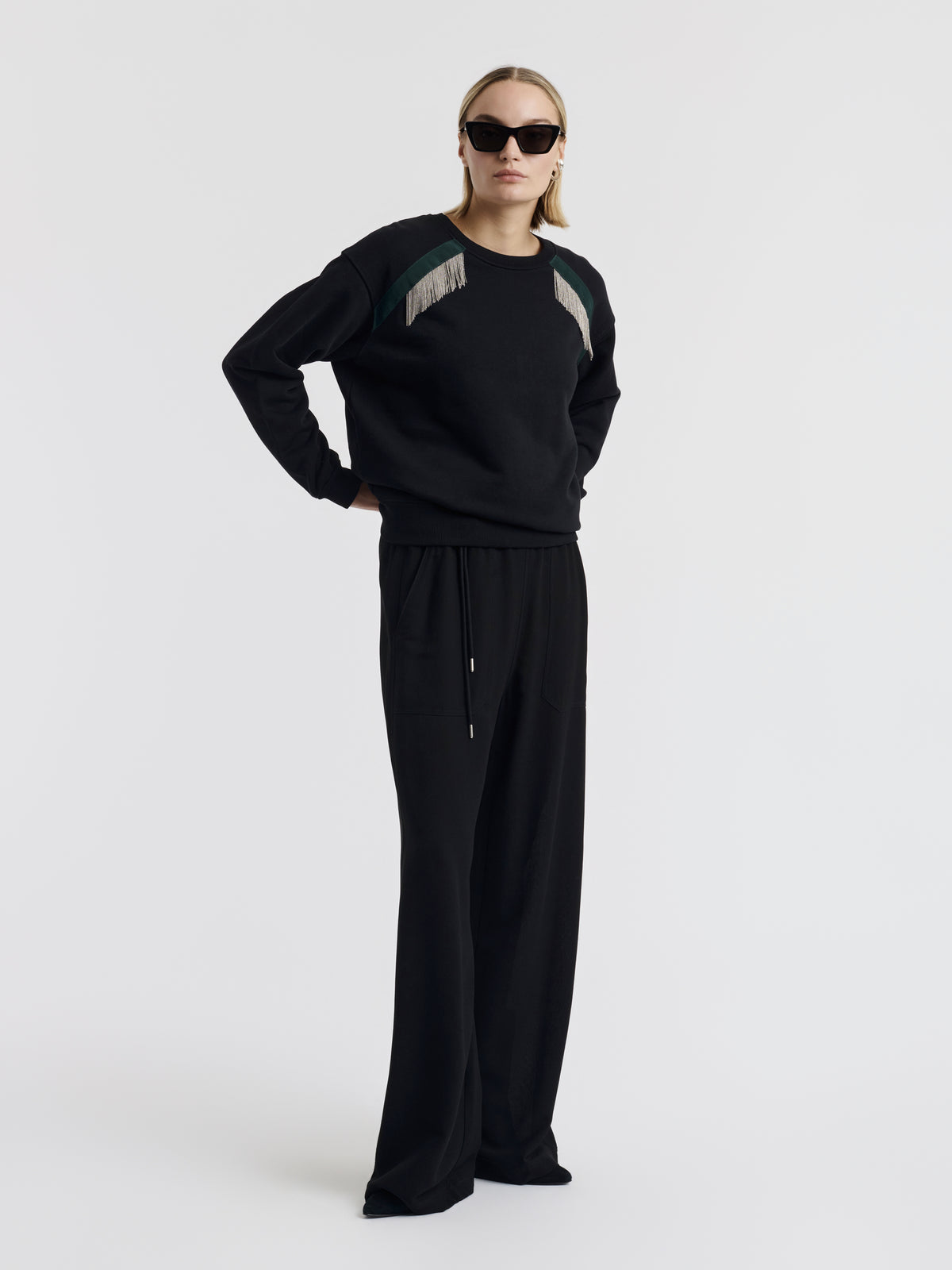 Black MARTY CHAINS sweatshirt with hand-embroidered chains, worn with black wide-leg trousers