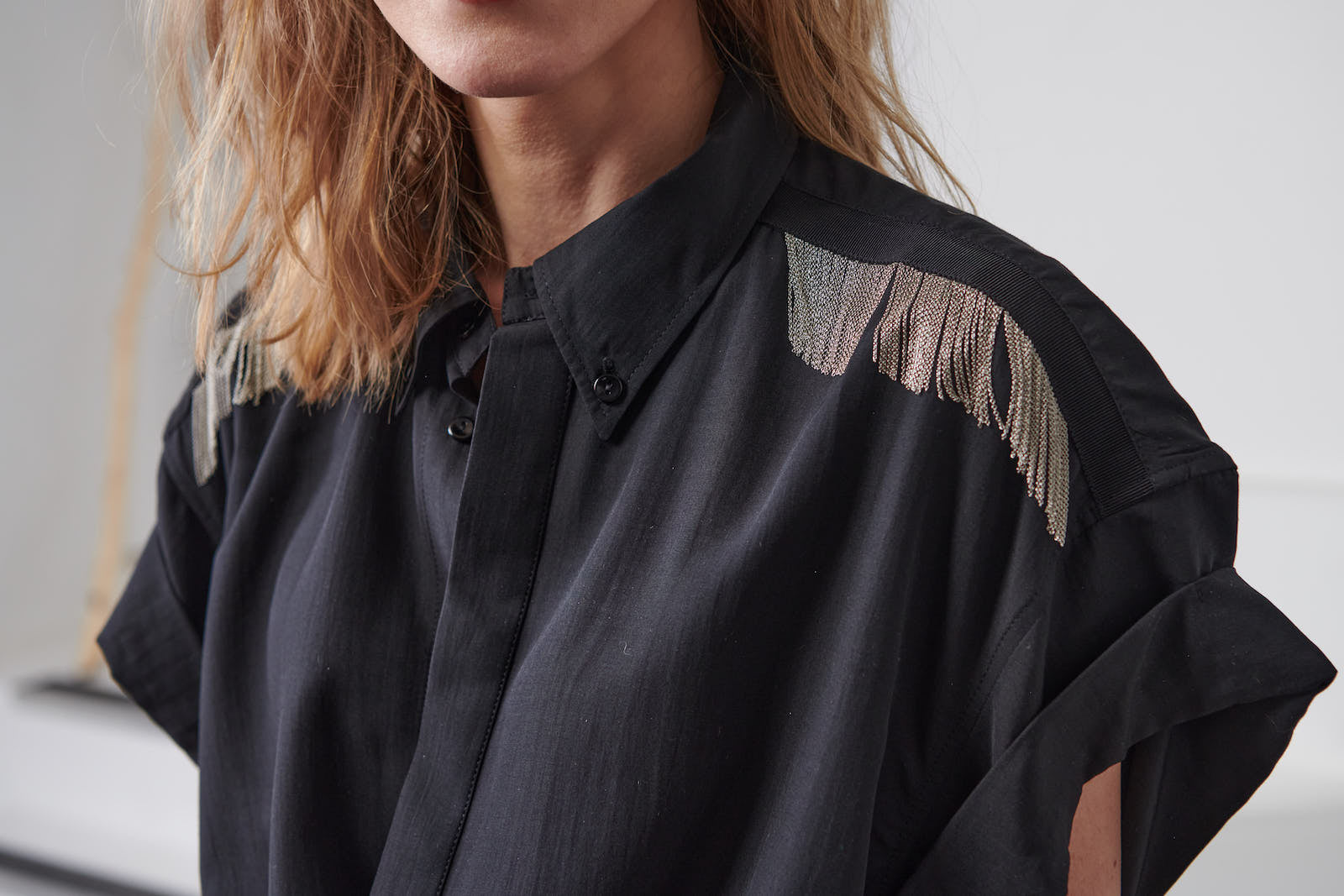 Oversized fluid black shirt dress for women. Signature hand-embroidered chains on the shoulders. Short rolled up sleeves, a shortened front pocket on the front. Belgian fashion made in Portugal.