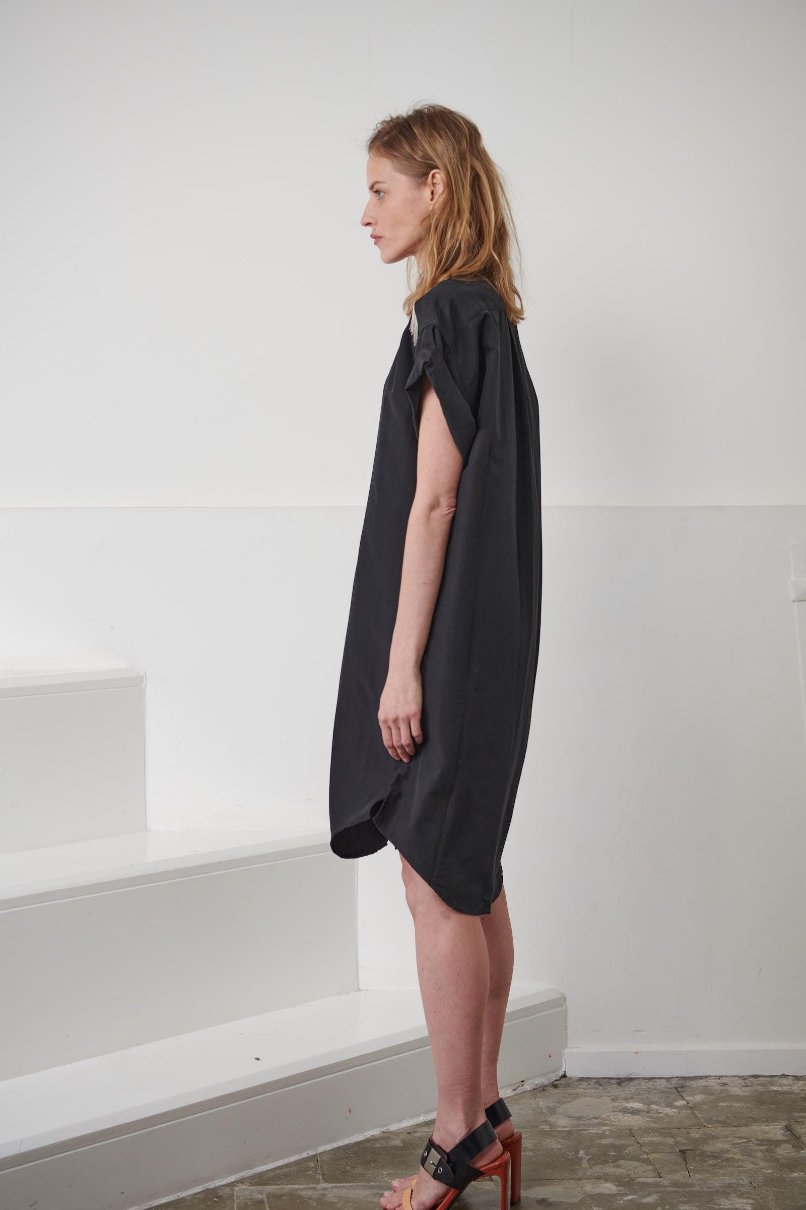 Oversized fluid black shirt dress for women. Signature hand-embroidered chains on the shoulders. Short rolled up sleeves, a shortened front pocket on the front. Belgian fashion made in Portugal.