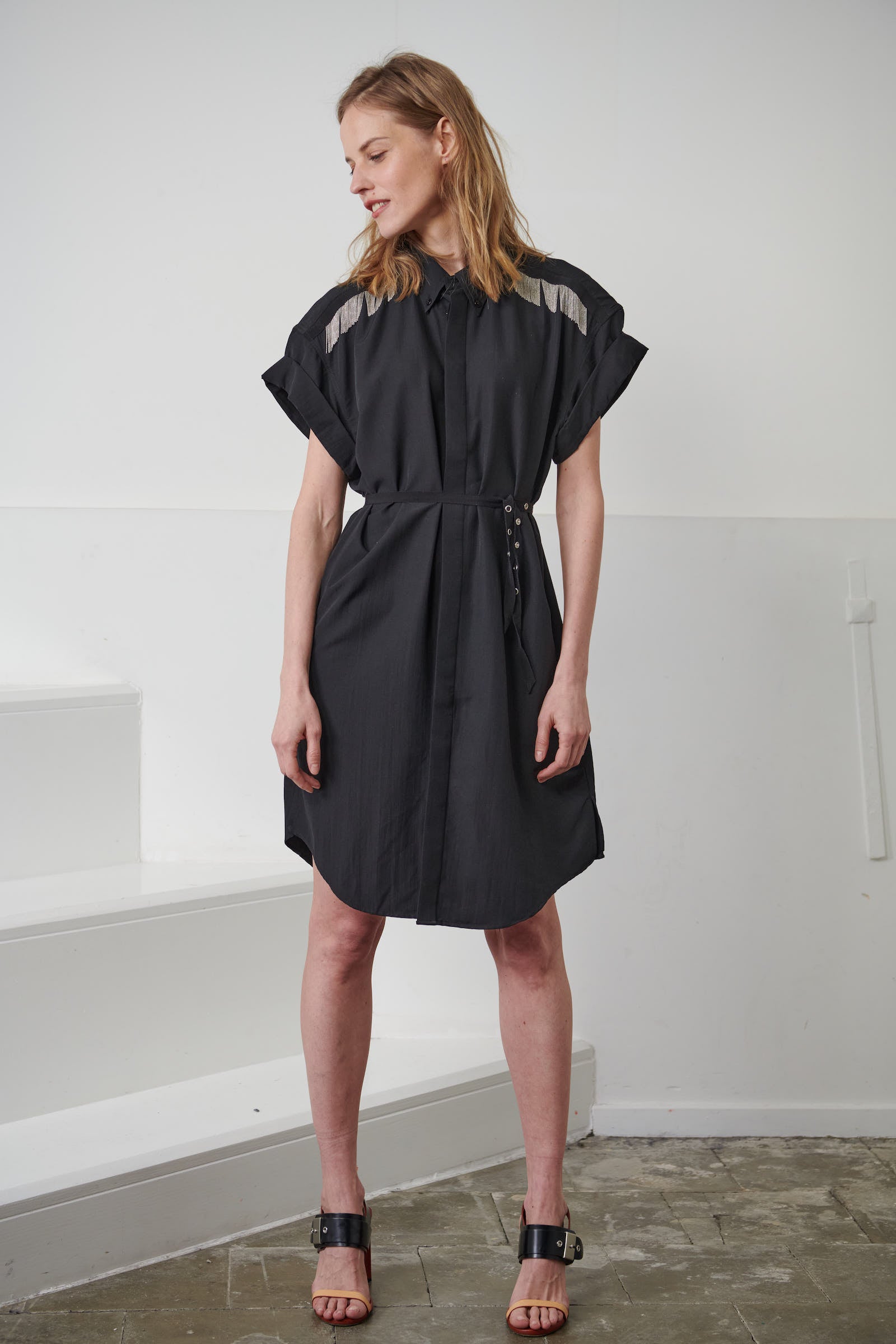 Oversized fluid black shirt dress for women. Signature hand-embroidered chains on the shoulders. Short rolled up sleeves, a shortened front pocket on the front. Belgian fashion made in Portugal.