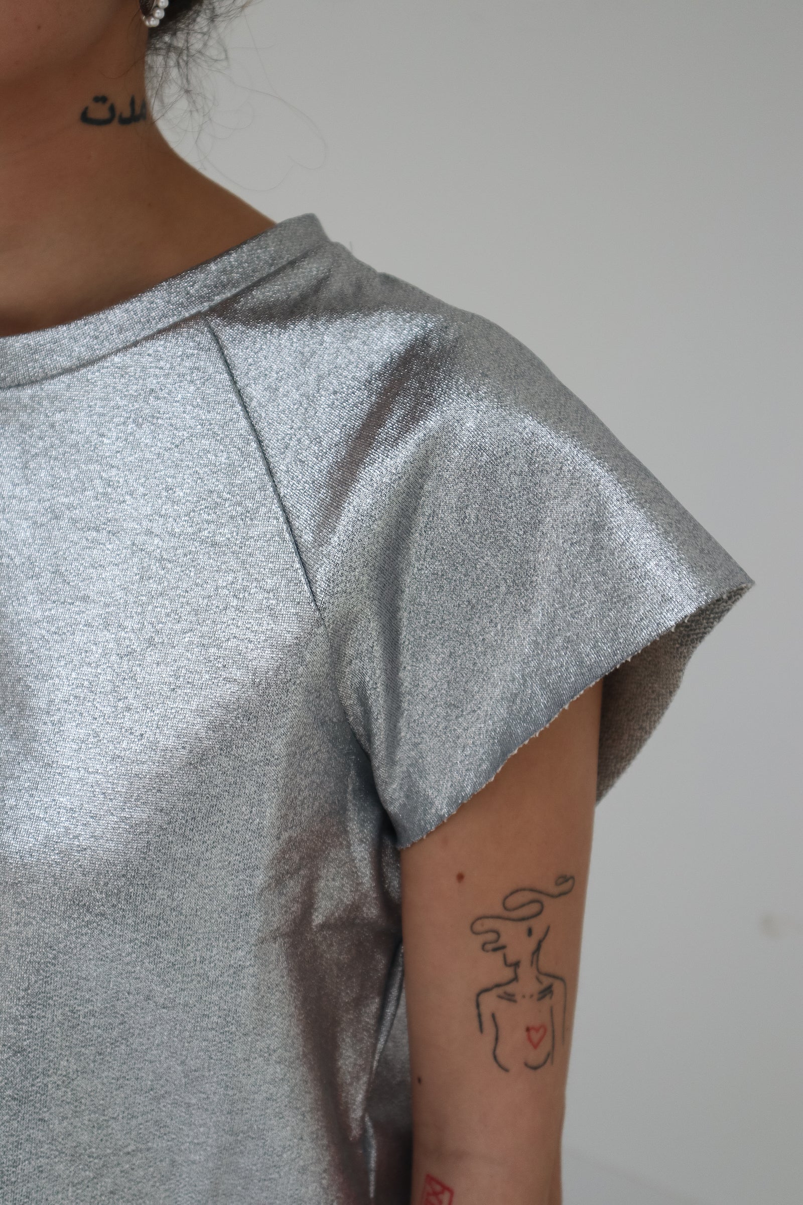Rock and shinny! For a special occasion, to party all night long, or just stand out a little more, the Nadine sweater/T-shirt was made for you! Go wild! It has a straight fit, slightly cropped, and features raw cut raglan sleeves and a raw cut hem. Made in a 100% silver coated cotton, in Portugal Louise is 170 cm tall and wears a size M