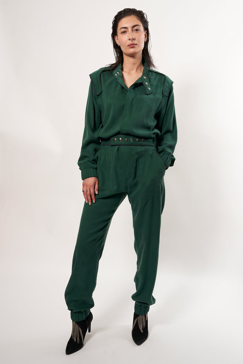 SARAH DE SAINT HUBERT Heritage racing jumpsuit with SDSH signature details. Dark green gros-grain trimming around the neck and waist belt. Iconic rows of metal snaps at the collar and waist. Wear it baggy for a boyish look. Wear it tightened at the waist for a more feminine look. Straight and relaxed fit. Black tencel (natural fibers). 100% tn. Made in Portugal