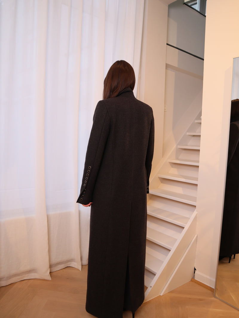 Crafted from 100% pure wool, this coat is a tribute to understated luxury. Its flowing silhouette whispers sophistication, enveloping you in warmth without compromise. Whether layered over tailored ensembles or paired with casual staples, it becomes an effortless extension of your style. A timeless piece designed for those who seek beauty in simplicity and grace in every step. Produced in Portugal in limited quantities.