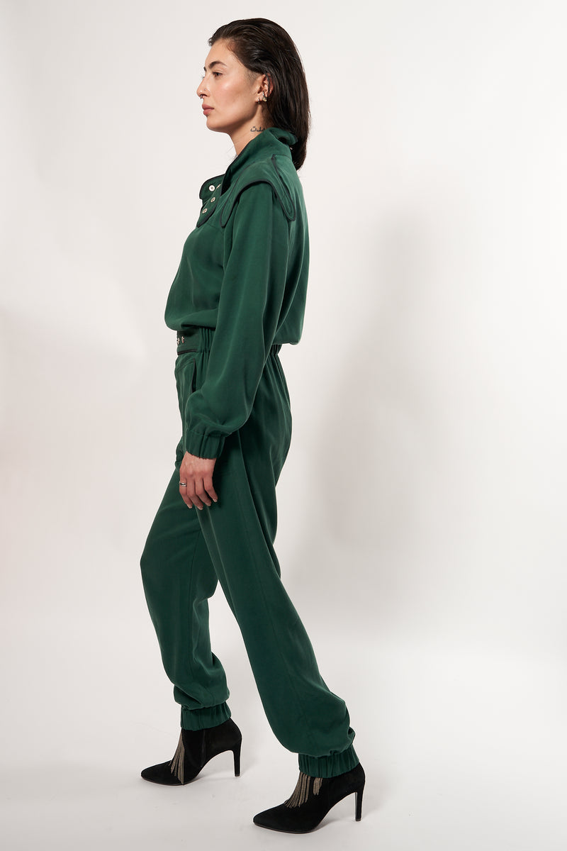 SARAH DE SAINT HUBERT Heritage racing jumpsuit with SDSH signature details. Dark green gros-grain trimming around the neck and waist belt. Iconic rows of metal snaps at the collar and waist. Wear it baggy for a boyish look. Wear it tightened at the waist for a more feminine look. Straight and relaxed fit. Black tencel (natural fibers). 100% tn. Made in Portugal