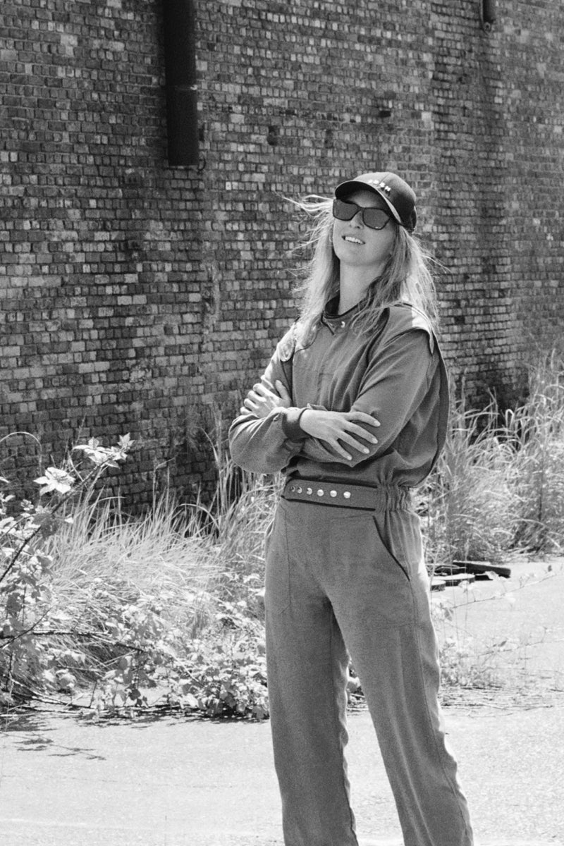 SARAH DE SAINT HUBERT Heritage racing jumpsuit with SDSH signature details. Dark green gros-grain trimming around the neck and waist belt. Iconic rows of metal snaps at the collar and waist. Wear it baggy for a boyish look. Wear it tightened at the waist for a more feminine look. Straight and relaxed fit. Khaki tencel (natural fibers). 100% tn. Designed in Belgium, Made in Portugal