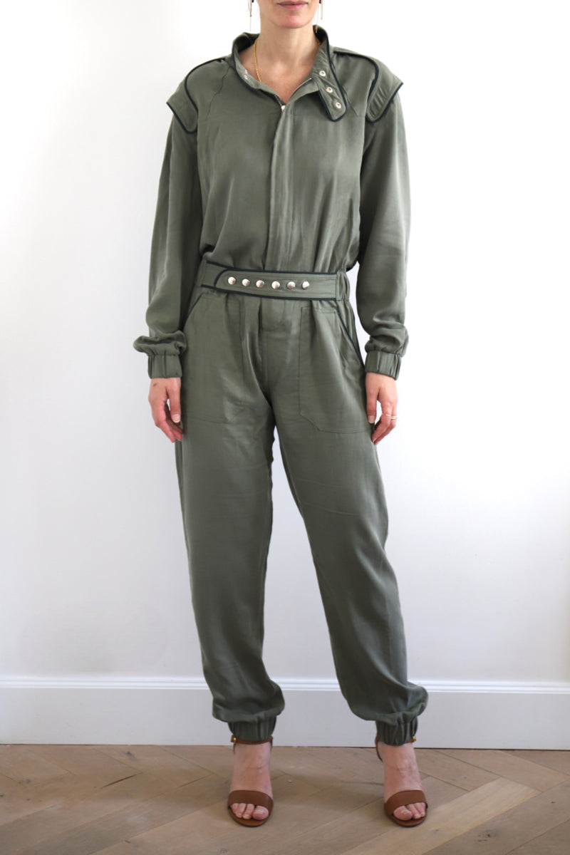 SARAH DE SAINT HUBERT Heritage racing jumpsuit with SDSH signature details. Dark green gros-grain trimming around the neck and waist belt. Iconic rows of metal snaps at the collar and waist. Wear it baggy for a boyish look. Wear it tightened at the waist for a more feminine look. Straight and relaxed fit. Khaki tencel (natural fibers). 100% tn. Designed in Belgium, Made in Portugal