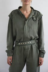 SARAH DE SAINT HUBERT Heritage racing jumpsuit with SDSH signature details. Dark green gros-grain trimming around the neck and waist belt. Iconic rows of metal snaps at the collar and waist. Wear it baggy for a boyish look. Wear it tightened at the waist for a more feminine look. Straight and relaxed fit. Khaki tencel (natural fibers). 100% tn. Designed in Belgium, Made in Portugal