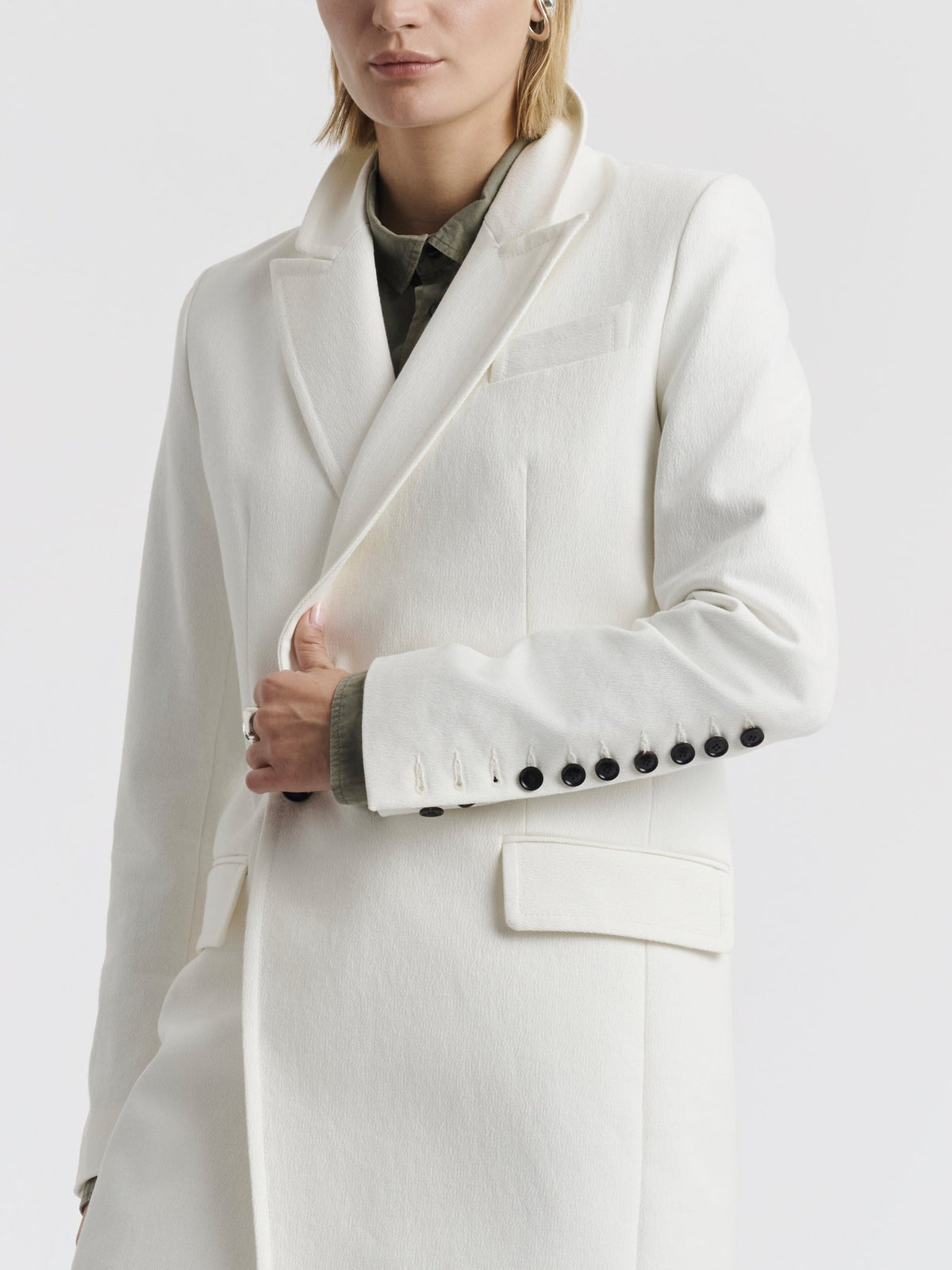 White cotton CARA coat with a row of black buttons on the cuff
