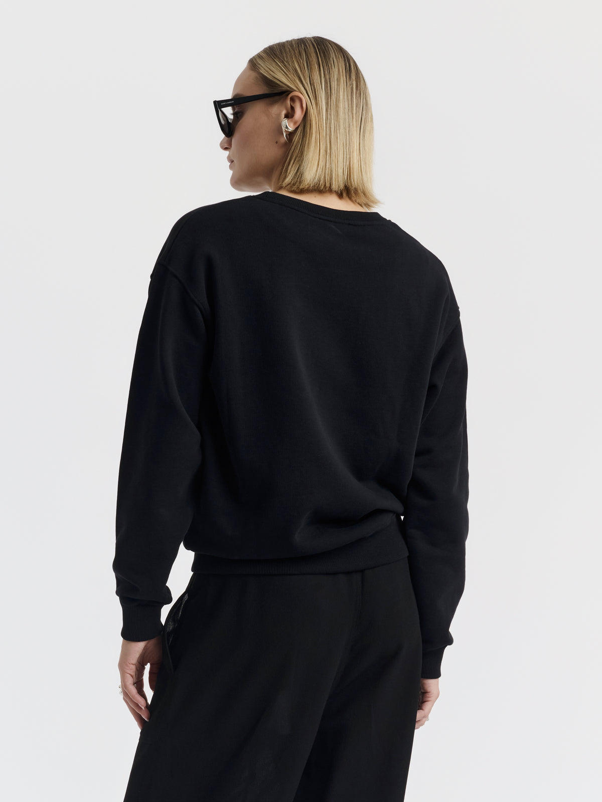 Black MARTY CHAINS sweatshirt with hand-embroidered chains, worn with black wide-leg trousers
