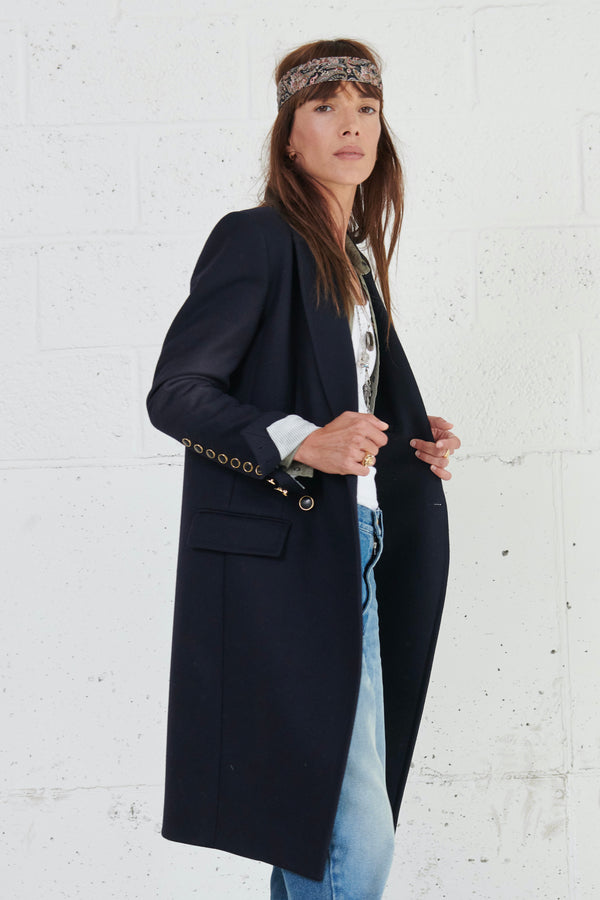 Navy wool double breasted tailored coat with iconic details. 2 front pockets. slit at the center back. navy striped viscose lining. signature extra-high buttonned cuffs with black/gold buttons. 100% wo. Made in Portugal